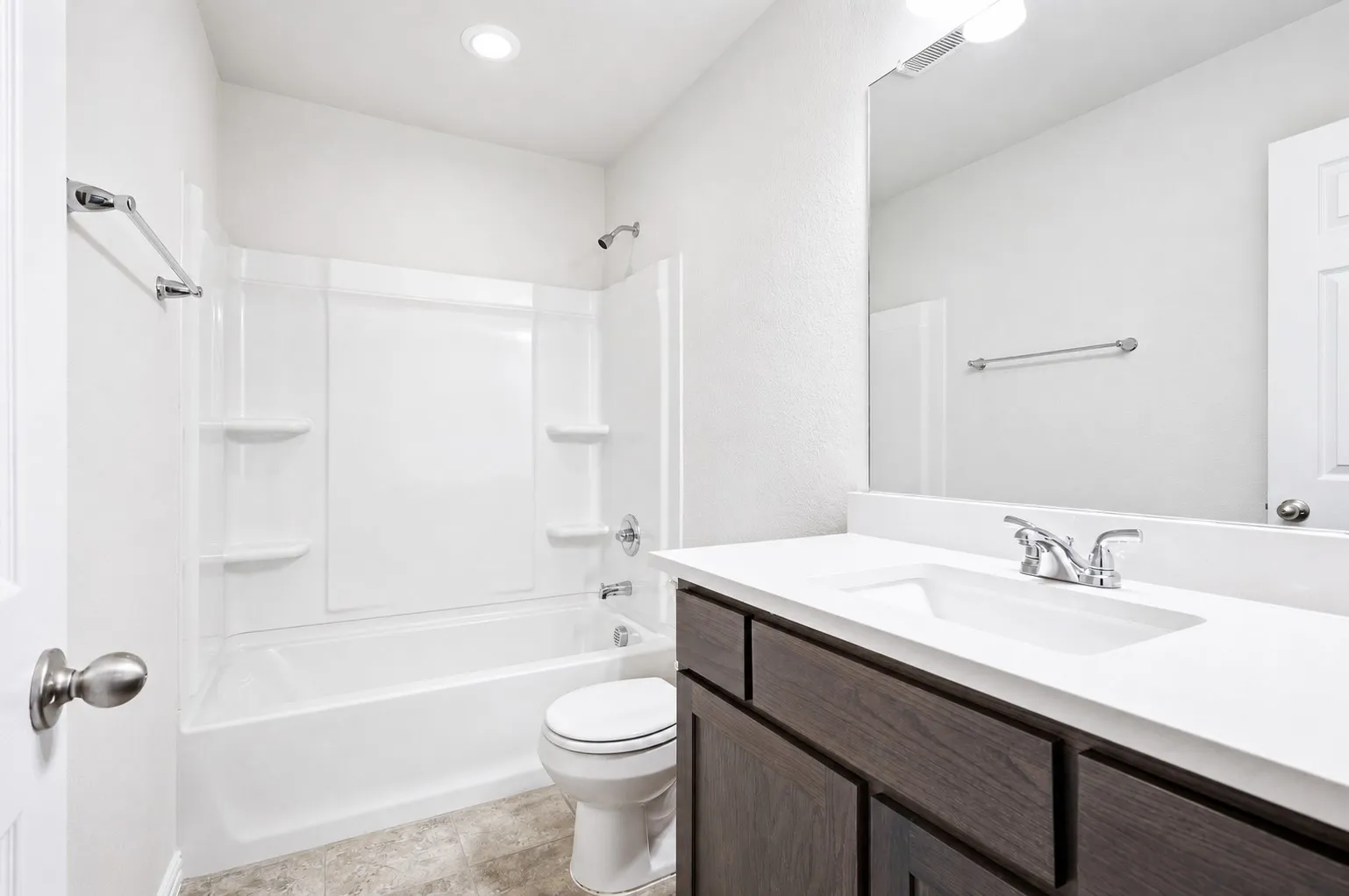 Bathroom featuring a built-in tub with shower, single vanity with a white countertop, and dark wood-finish cabinetry