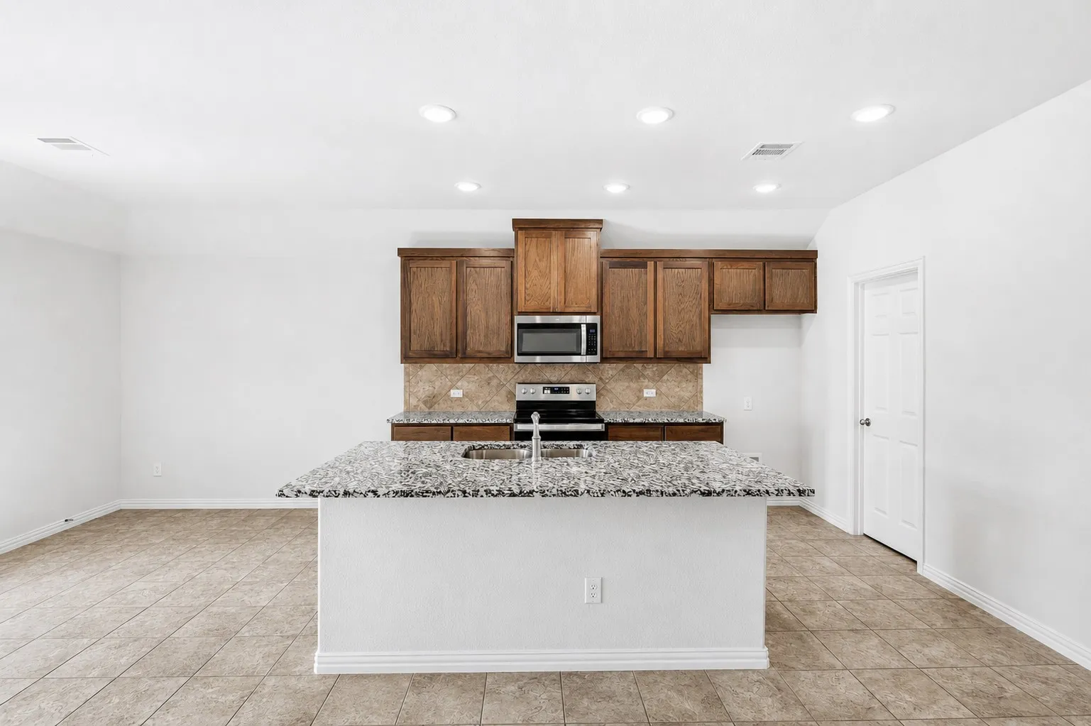 Kitchen featuring a center island with a sink, granite countertops, and wood cabinetry