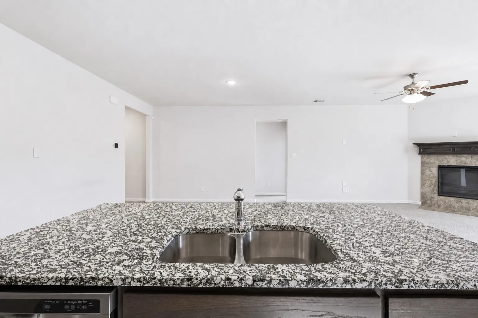 Kitchen island with speckled countertop, dual basin stainless steel sink, and stainless steel faucet