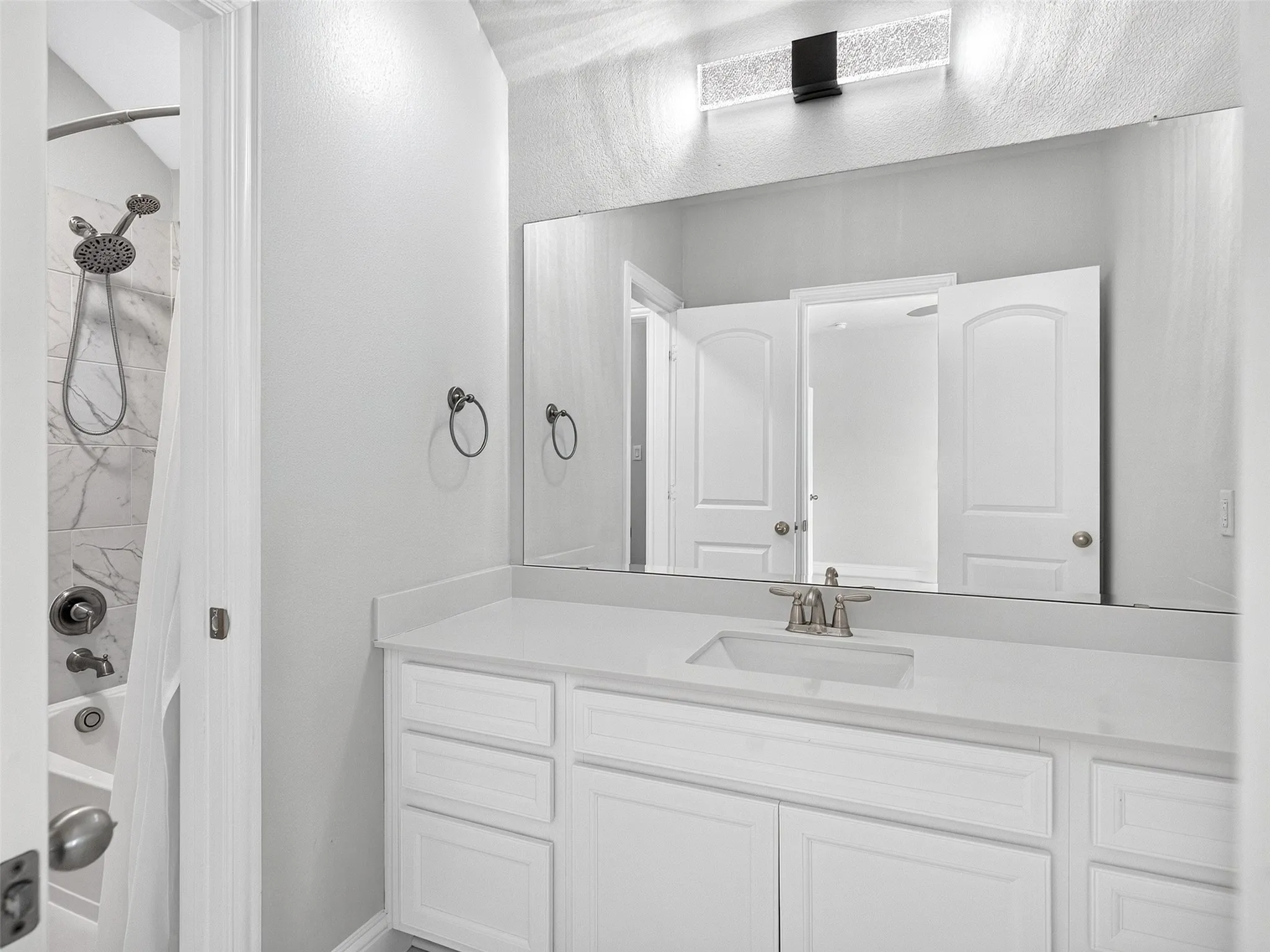 Jack & Jill Bathroom featuring a single vanity with an integrated sink, a large mirror, and a modern light fixture