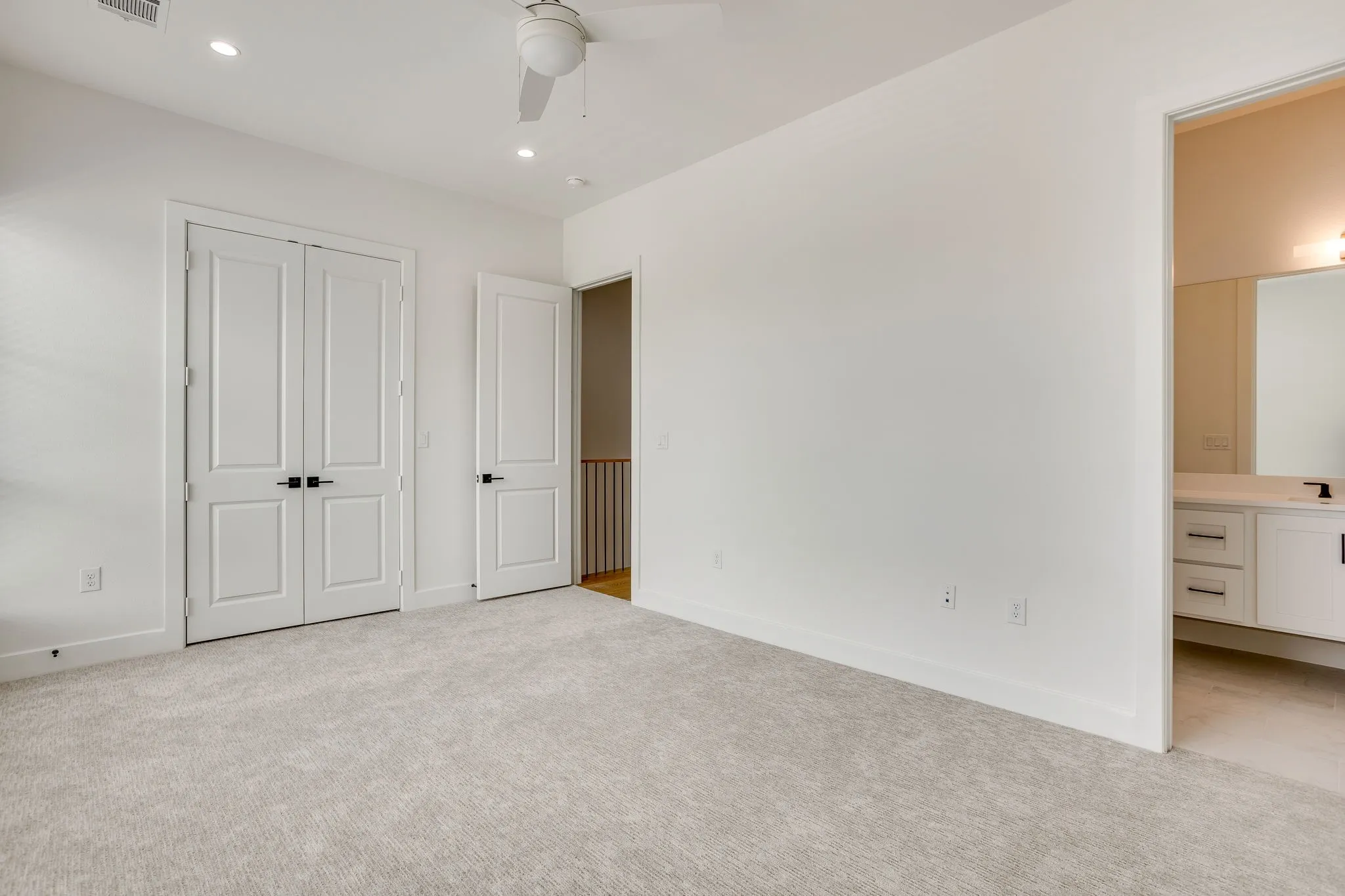 Neutral-toned carpeting paired with white walls, a white ceiling fan, and recessed lighting