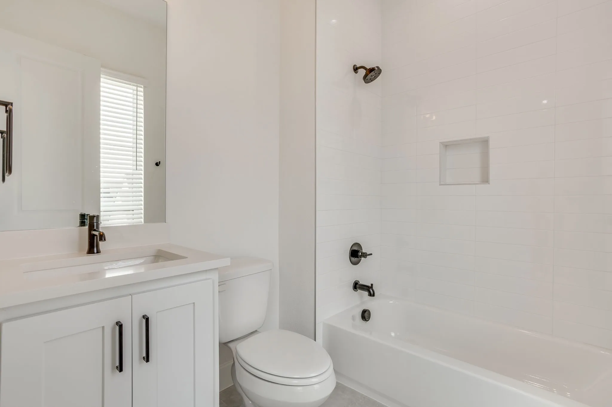 Contemporary bathroom featuring a built-in tub with white subway tile surround, integrated shower niche, and matte black fixtures