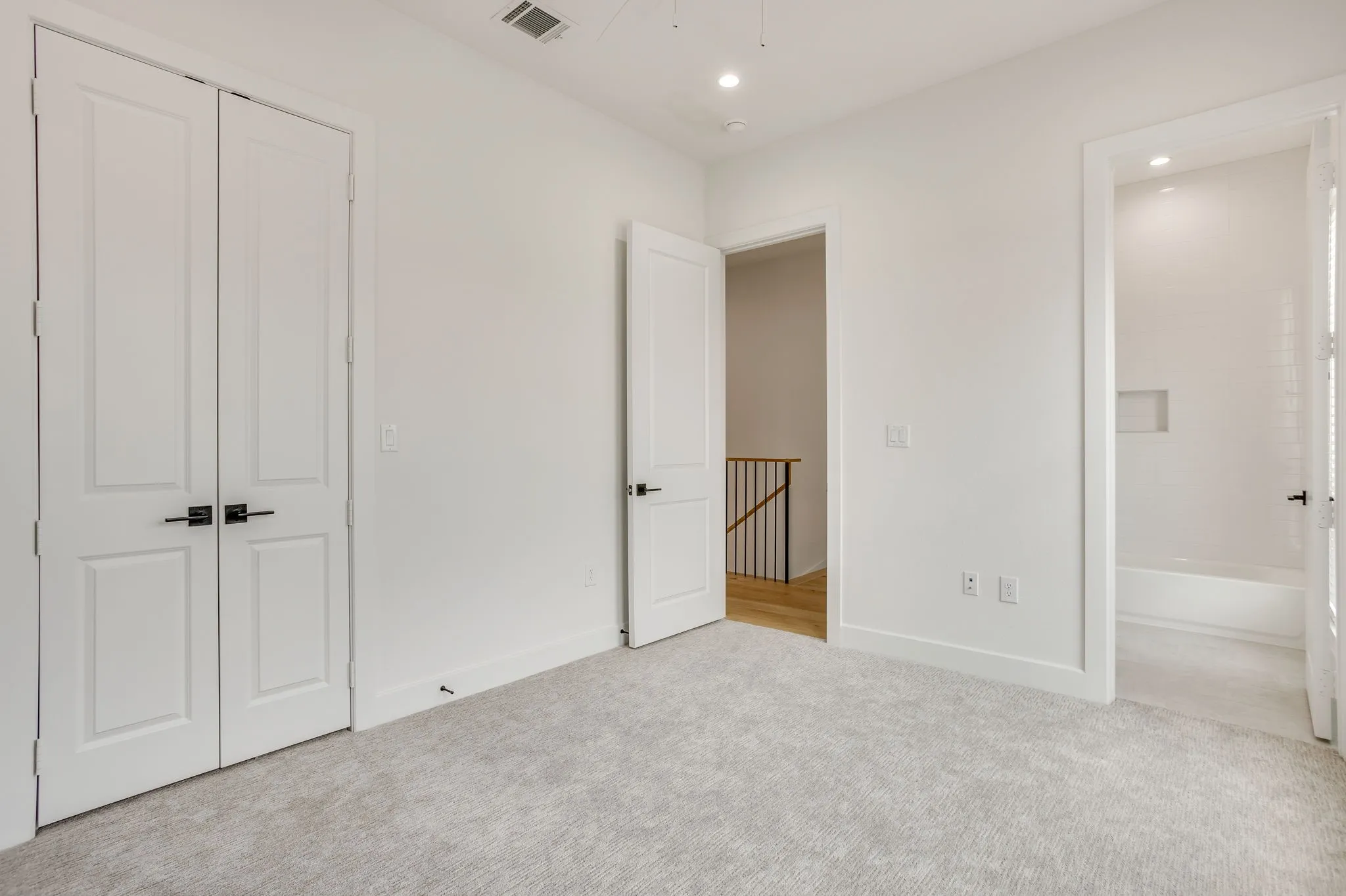 Spacious room with light gray carpet, recessed lighting, white walls, and white trim