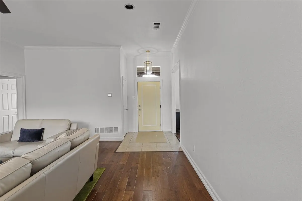 Entryway featuring wood-finish flooring, a light-toned door, a decorative pendant light fixture, and tile flooring at the entrance