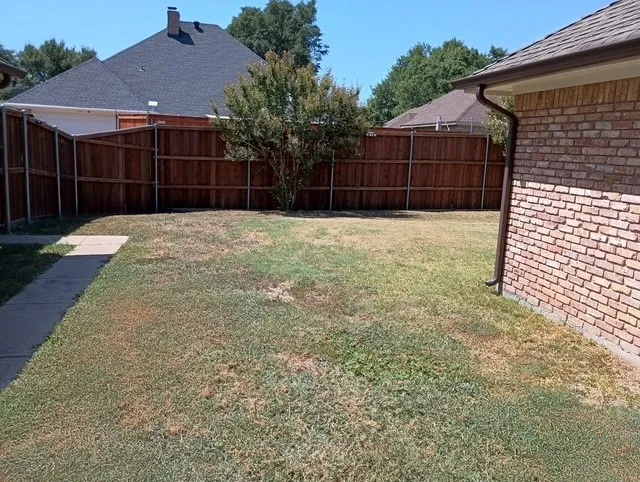 Spacious side of backyard enclosed by wood-finish privacy fencing
