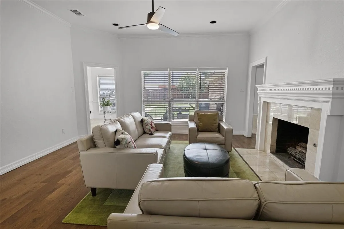 Living Room featuring a classic fireplace with a detailed mantel, wood-finish flooring, and crown molding