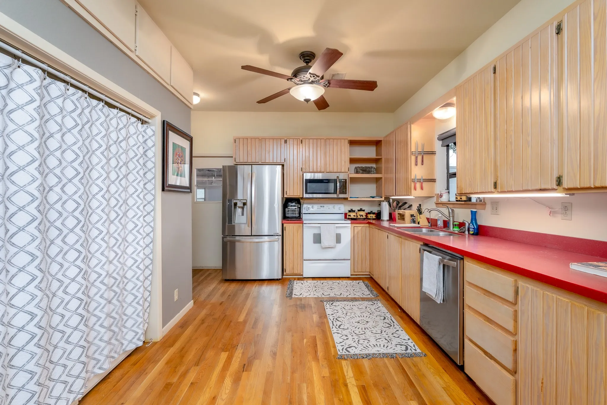 Kitchen featuring wood-finish flooring, light wood cabinetry, and red countertops