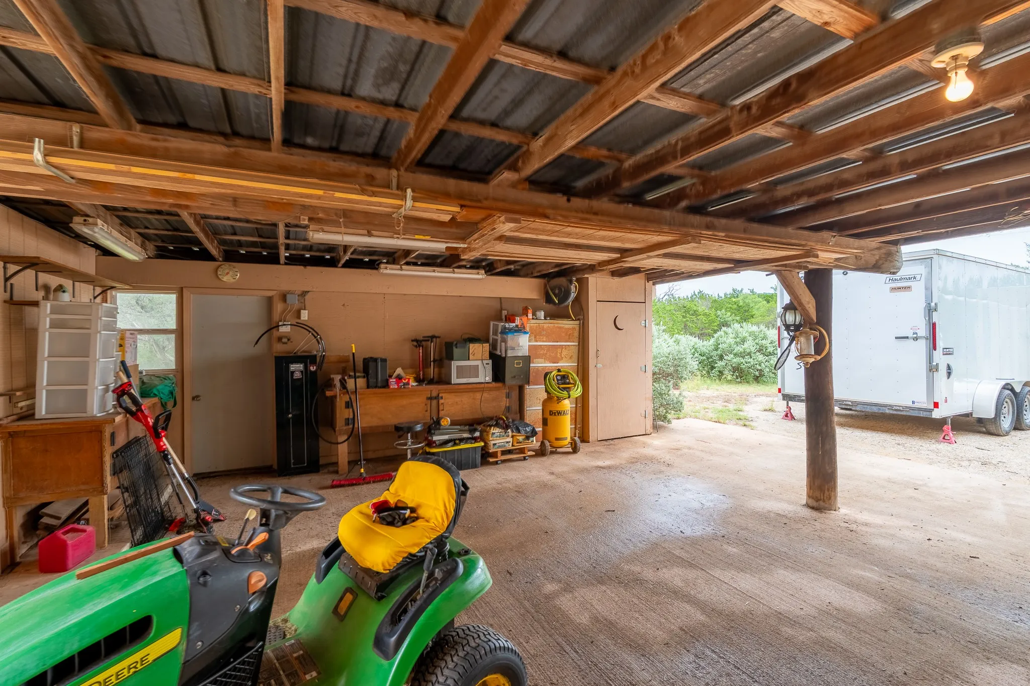 Covered outdoor space featuring a corrugated metal roof supported by wood beams and posts