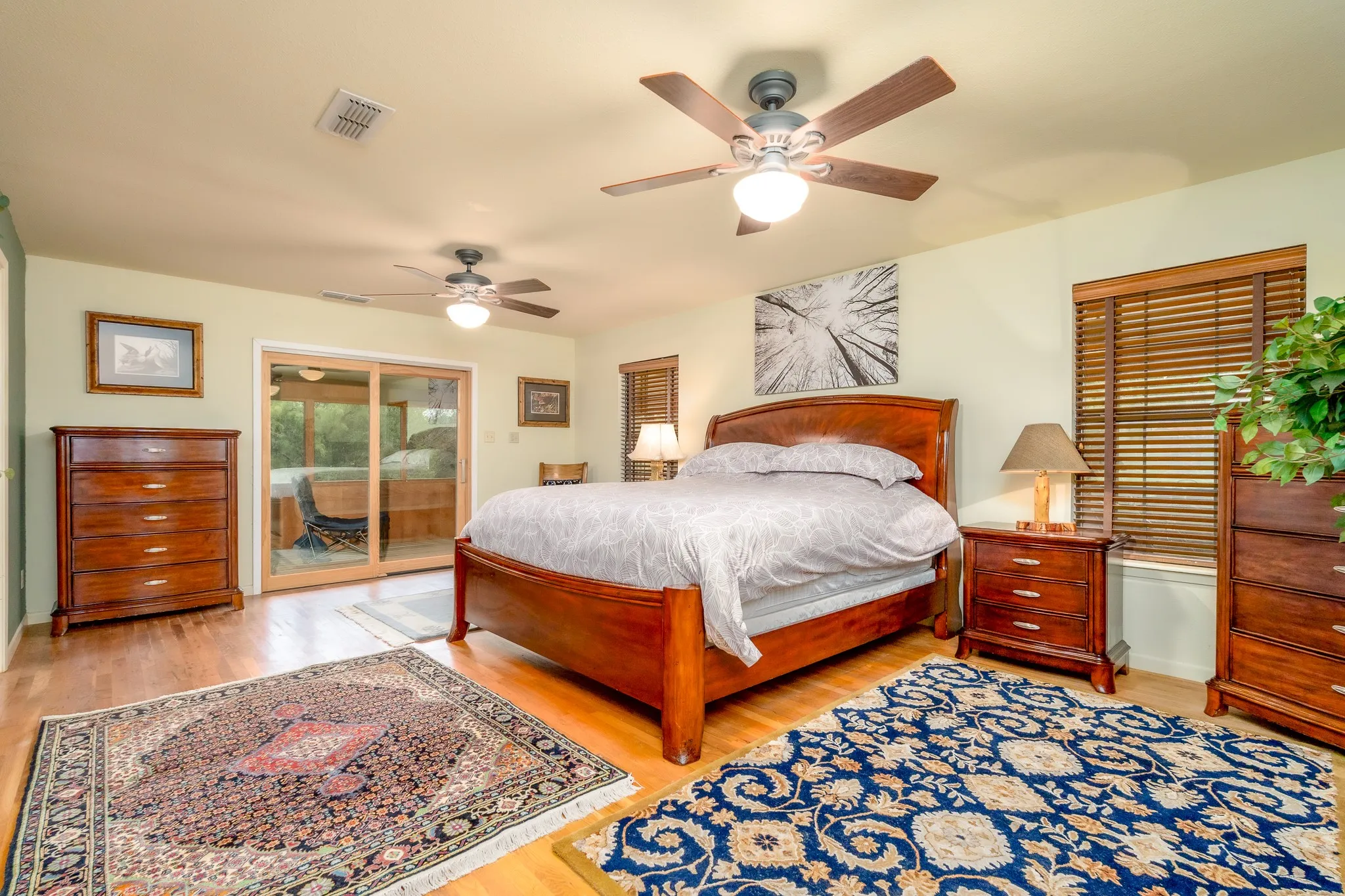 Spacious room featuring wood-finish flooring, light-toned walls, and multiple ceiling fans with integrated lighting