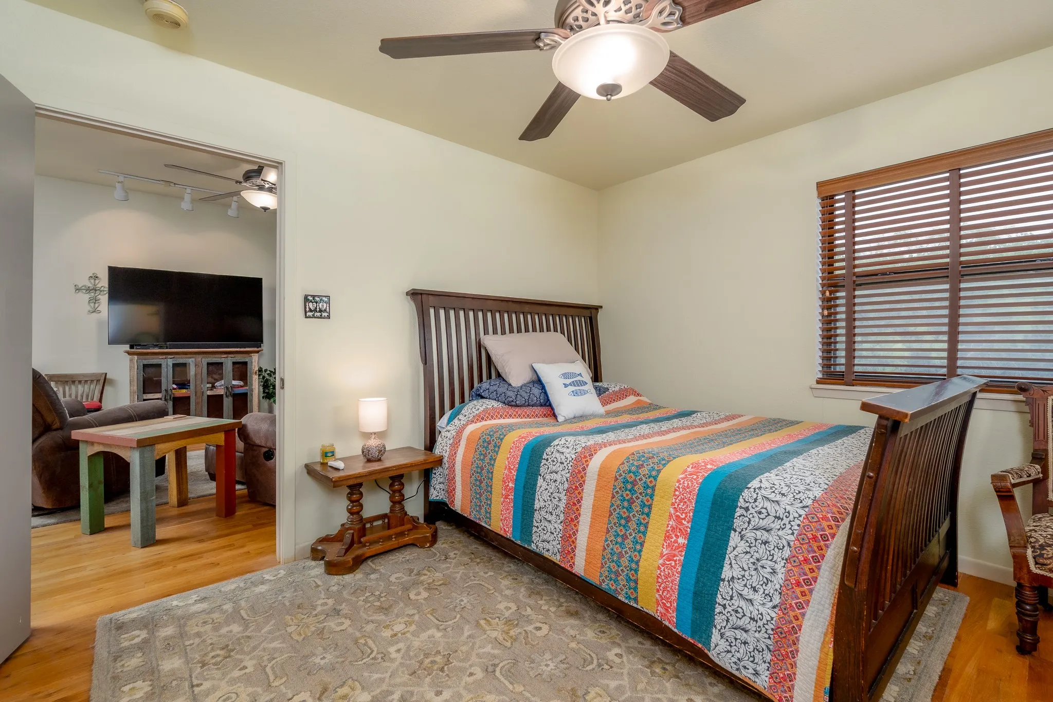 Bedroom featuring light-toned walls, a ceiling fan with integrated lighting, and a window with wooden blinds