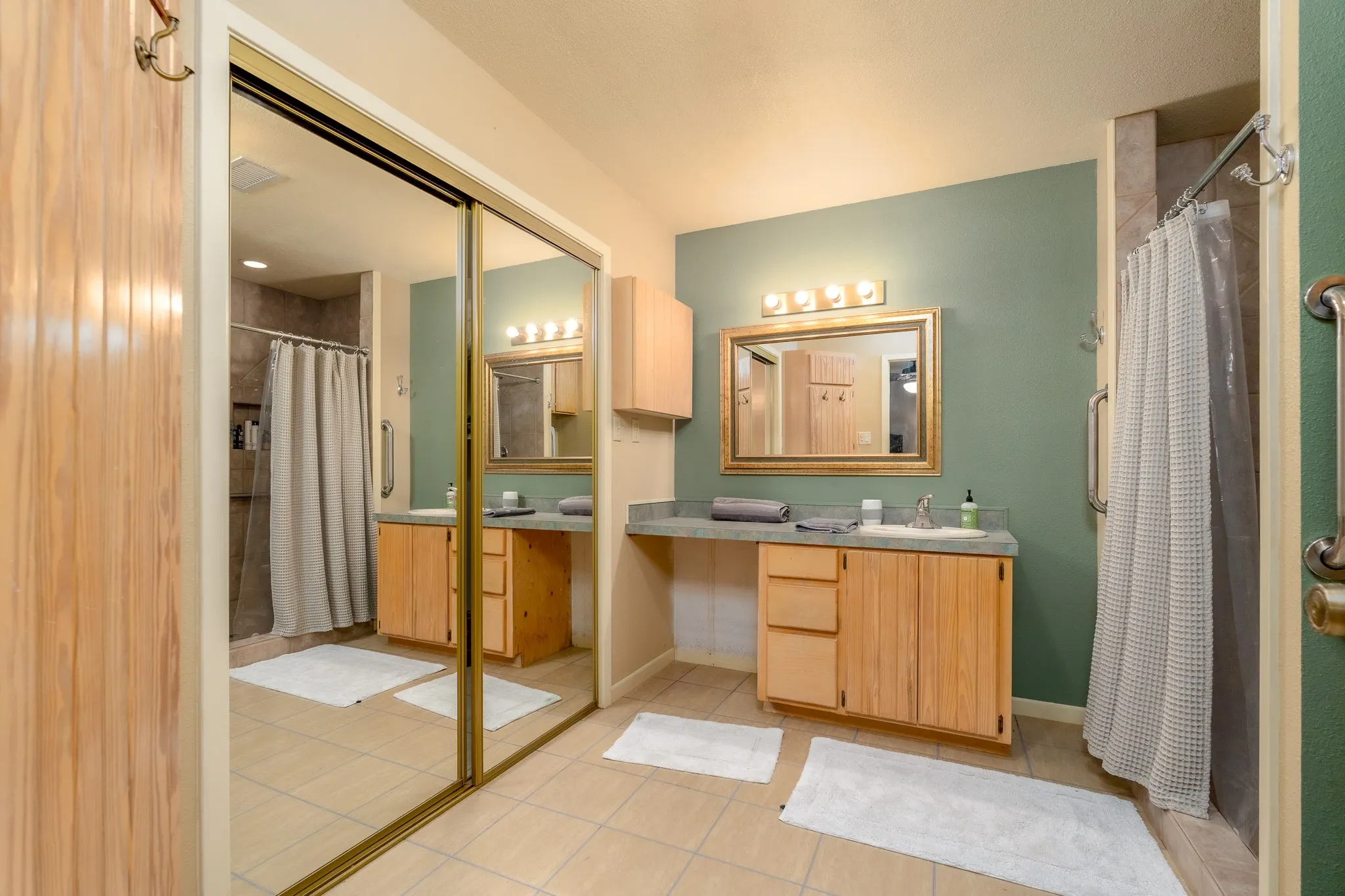 Bathroom featuring dual vanity areas with wood cabinetry and light-toned countertops