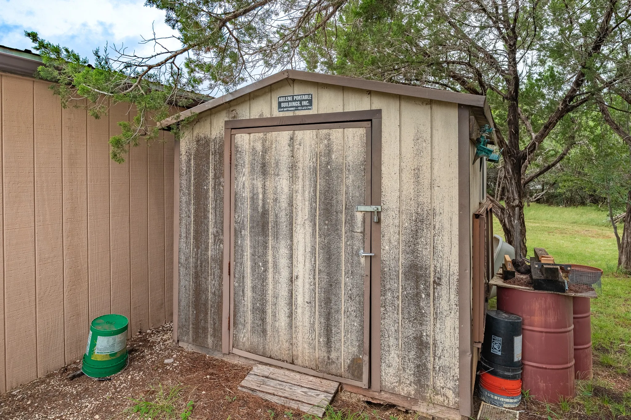 Wood-sided storage shed featuring a single door entry with latch hardware