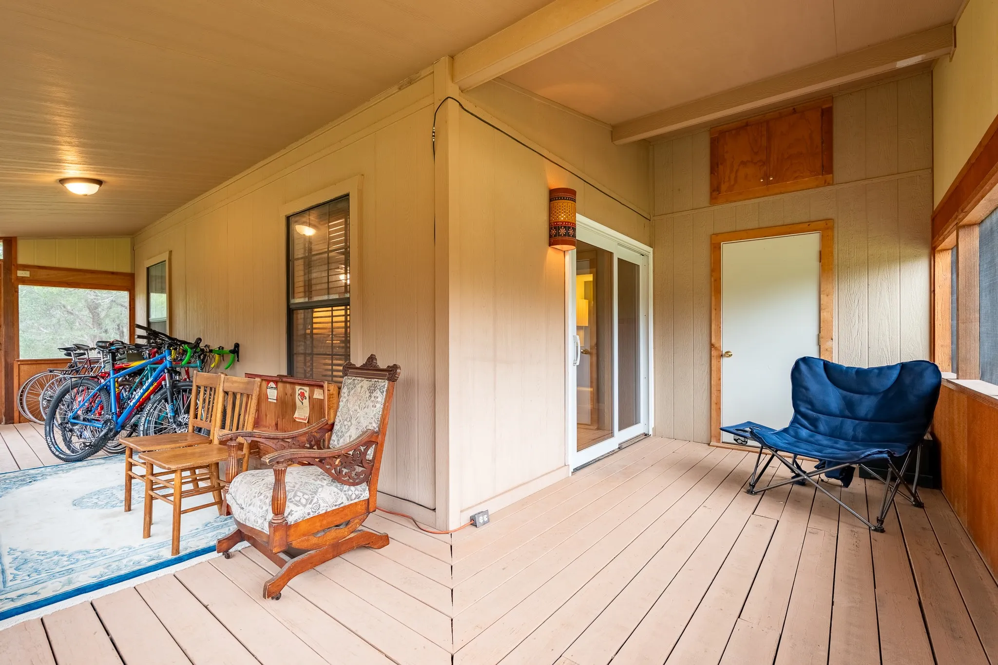 Spacious covered porch featuring light-colored decking, a sliding glass door, and an exterior door