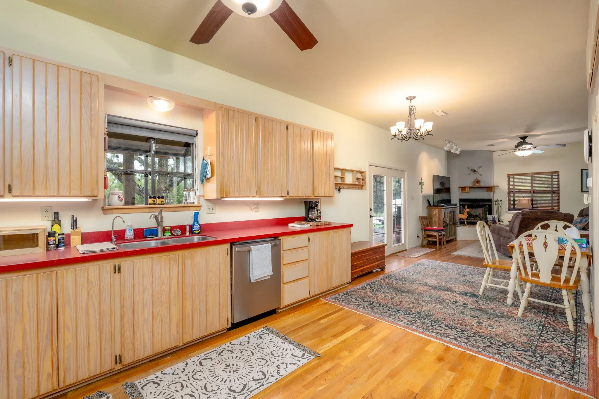 Kitchen featuring wood-finish cabinetry, a stainless steel dishwasher, and red countertops
