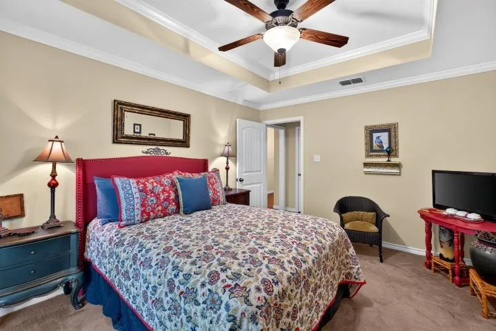 Carpeted room featuring a tray ceiling with crown molding and a ceiling fan