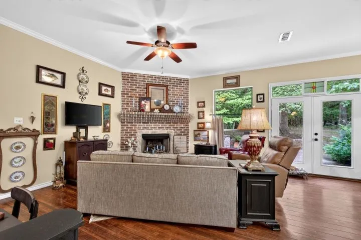 Spacious interior featuring wood-finish flooring, a brick fireplace, and a ceiling fan