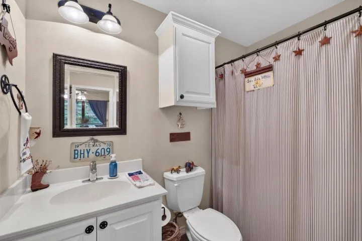Bathroom featuring a single-sink vanity with white cabinetry, a framed mirror, and an overhead light fixture