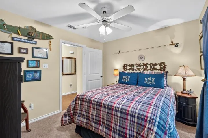 Inviting bedroom featuring neutral wall paint, carpet flooring, a ceiling fan, and a white paneled door