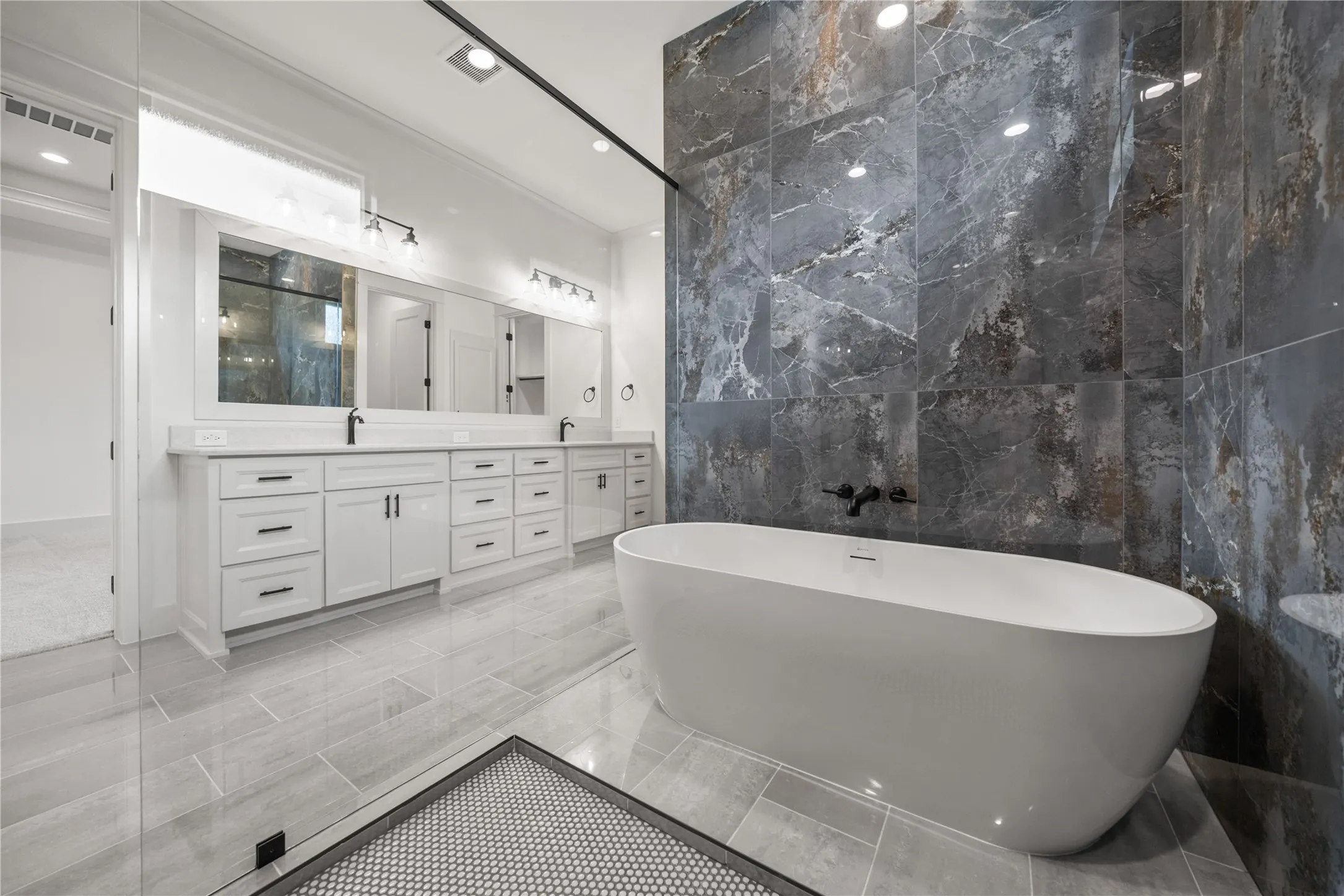 Freestanding soaking tub with dark wall-mounted fixtures