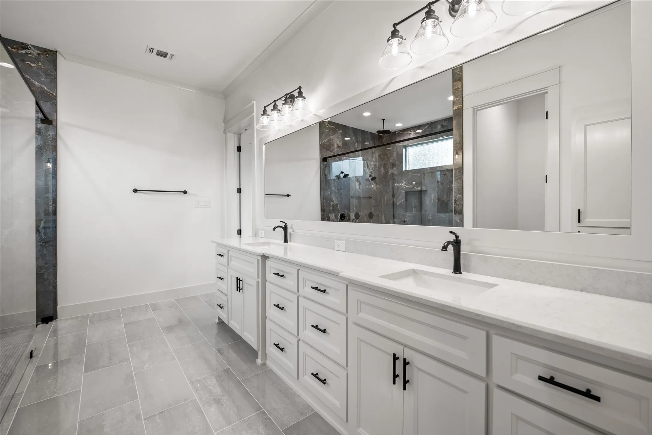 Dual vanity with white cabinetry, matte black hardware, and stone countertops