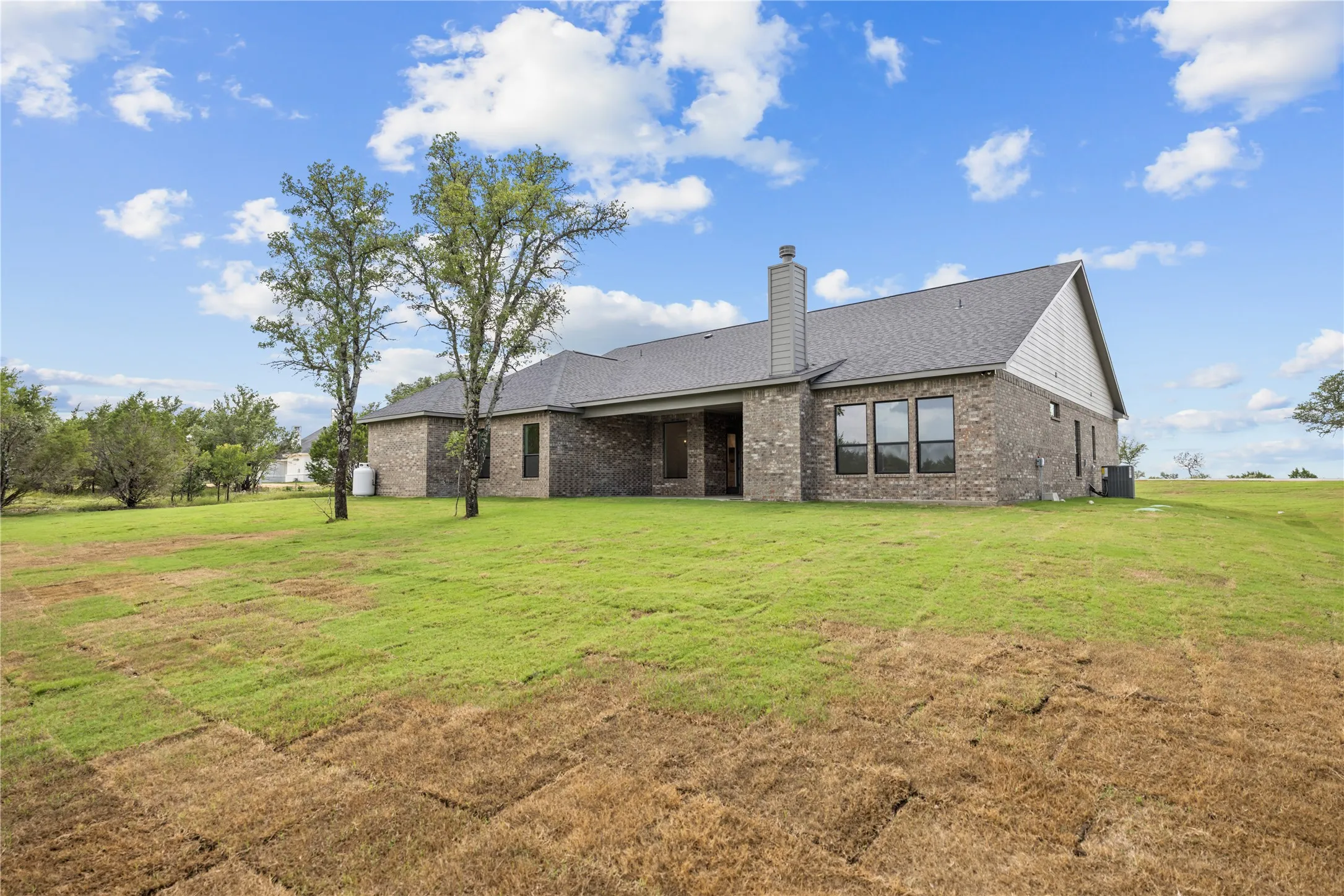 Expansive yard space surrounds this residence, featuring a brick and siding exterior with a shingle roof
