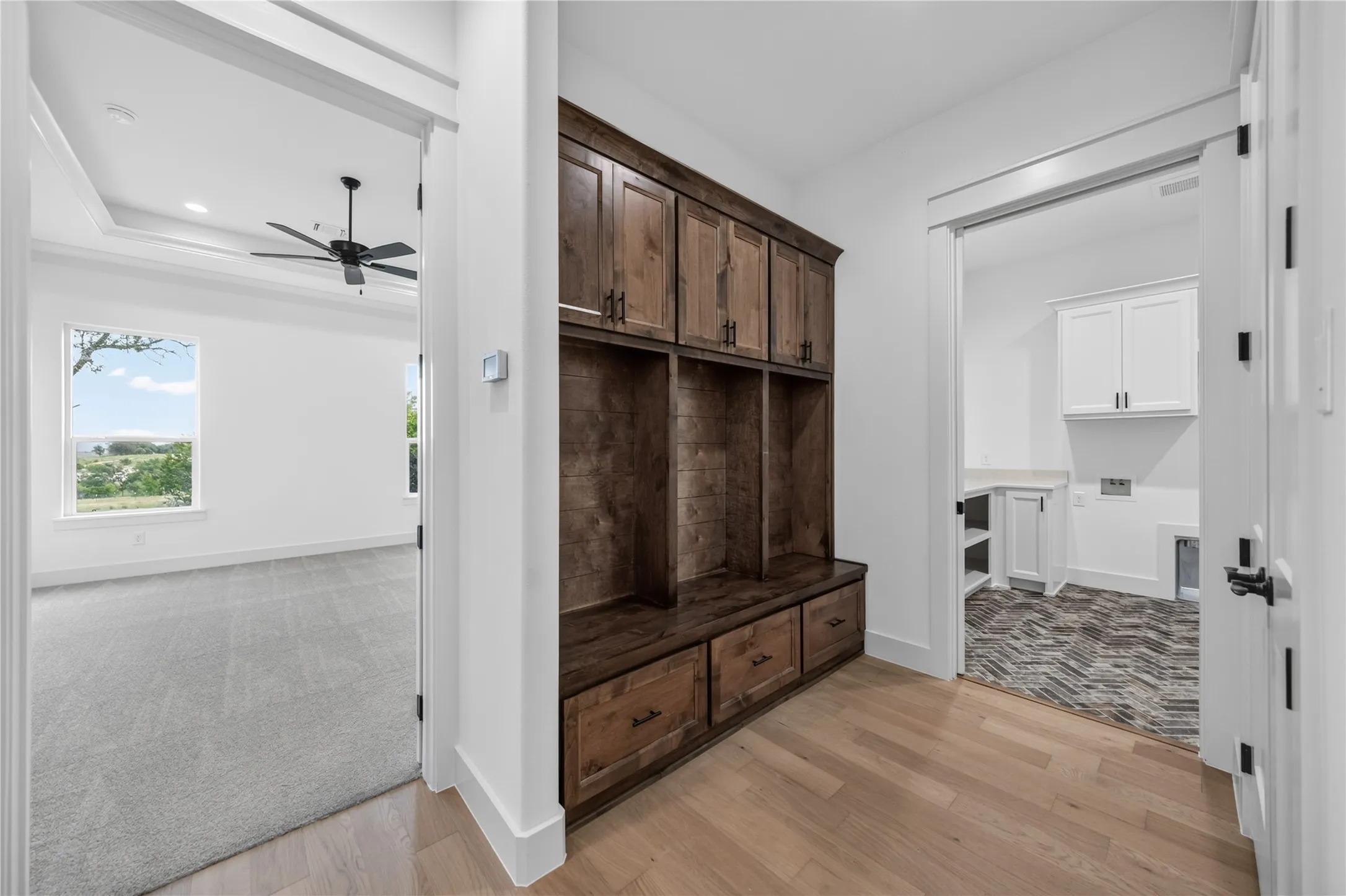 Built-in dark wood cabinetry with integrated bench seating, light wood-finish flooring, and white interior walls