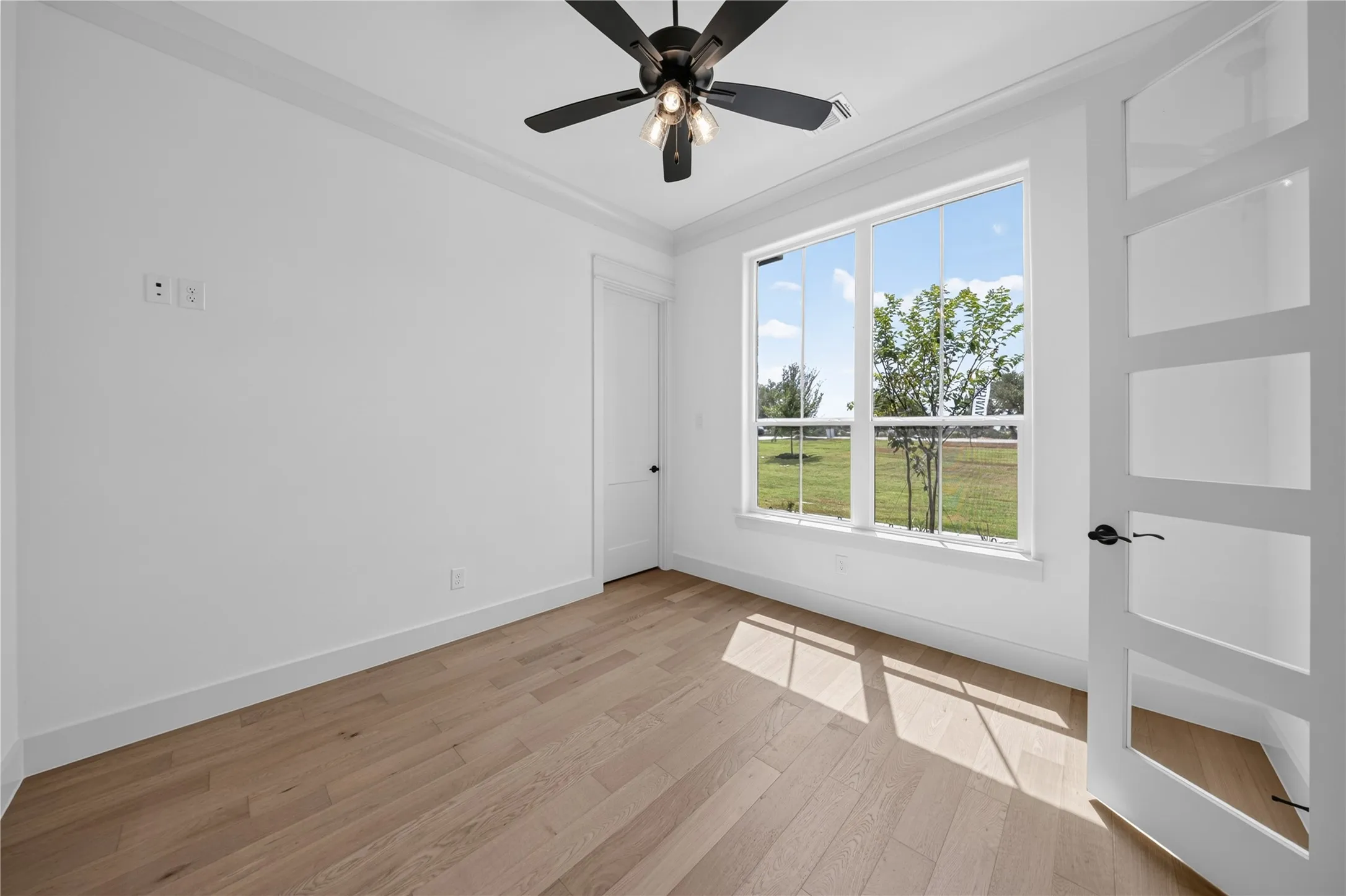 Light wood-finish flooring complements the crisp white walls and crown molding