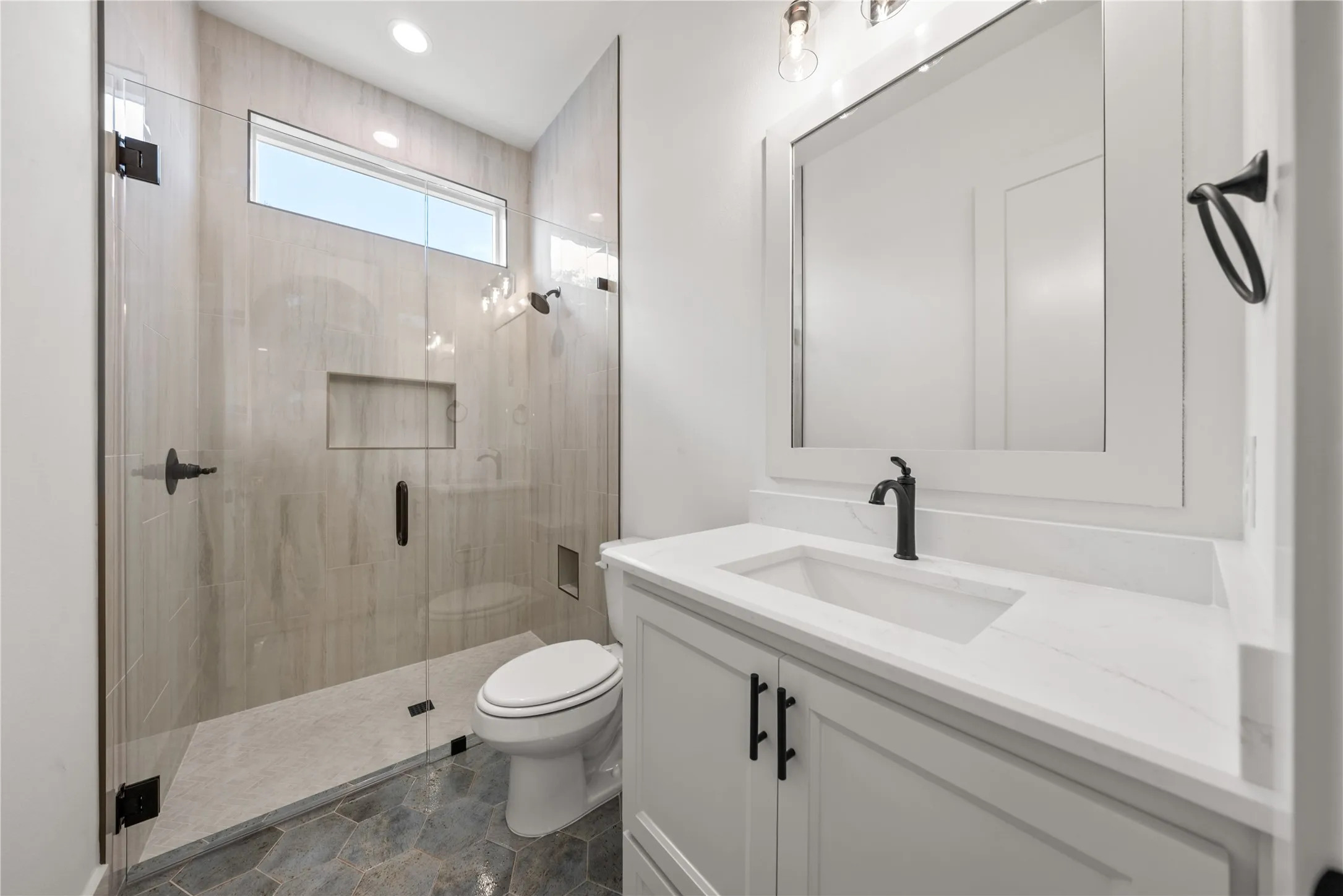 Contemporary bathroom featuring a frameless glass shower enclosure with a transom window