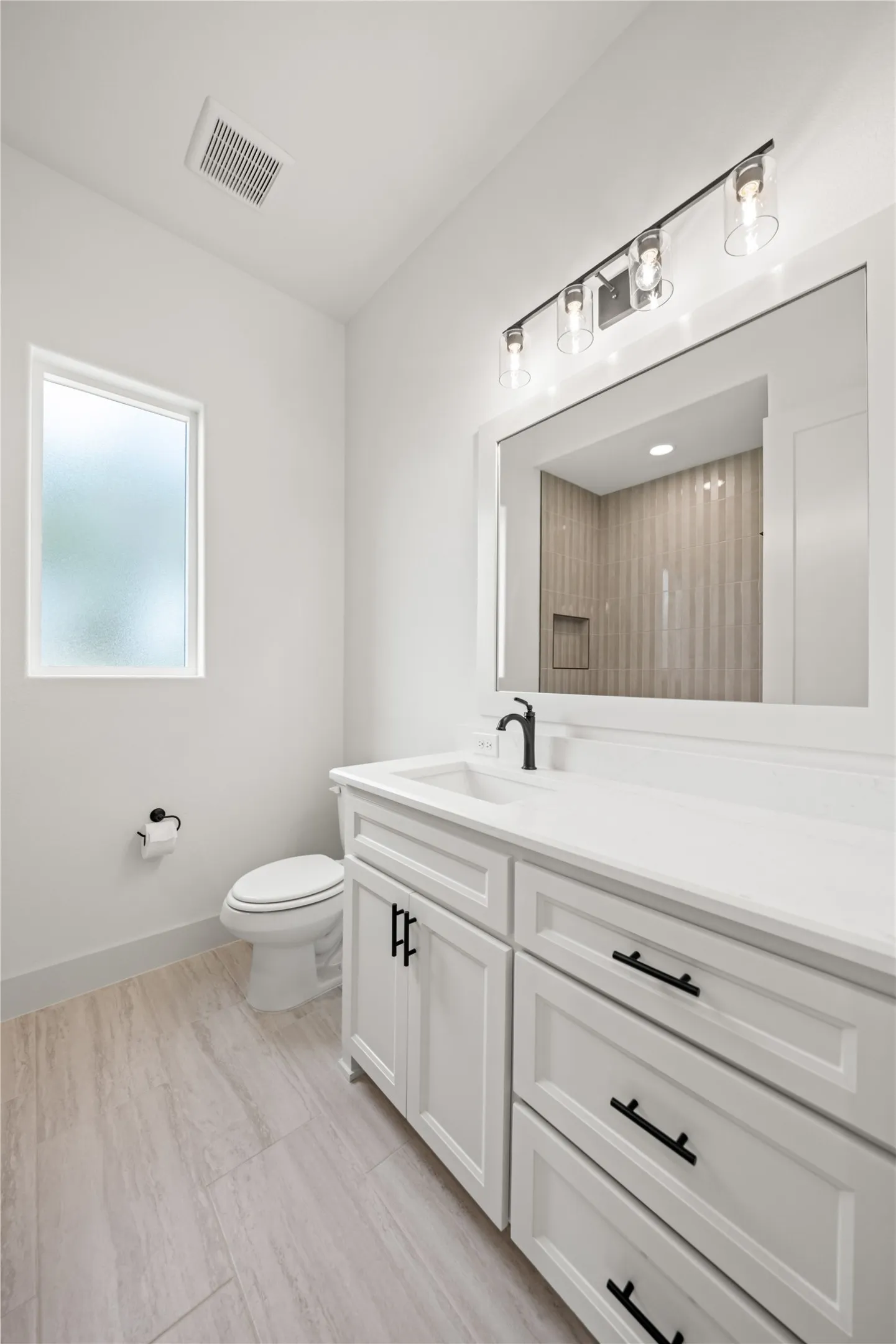 Bathroom featuring a white vanity with integrated sink, black fixtures, and a framed mirror
