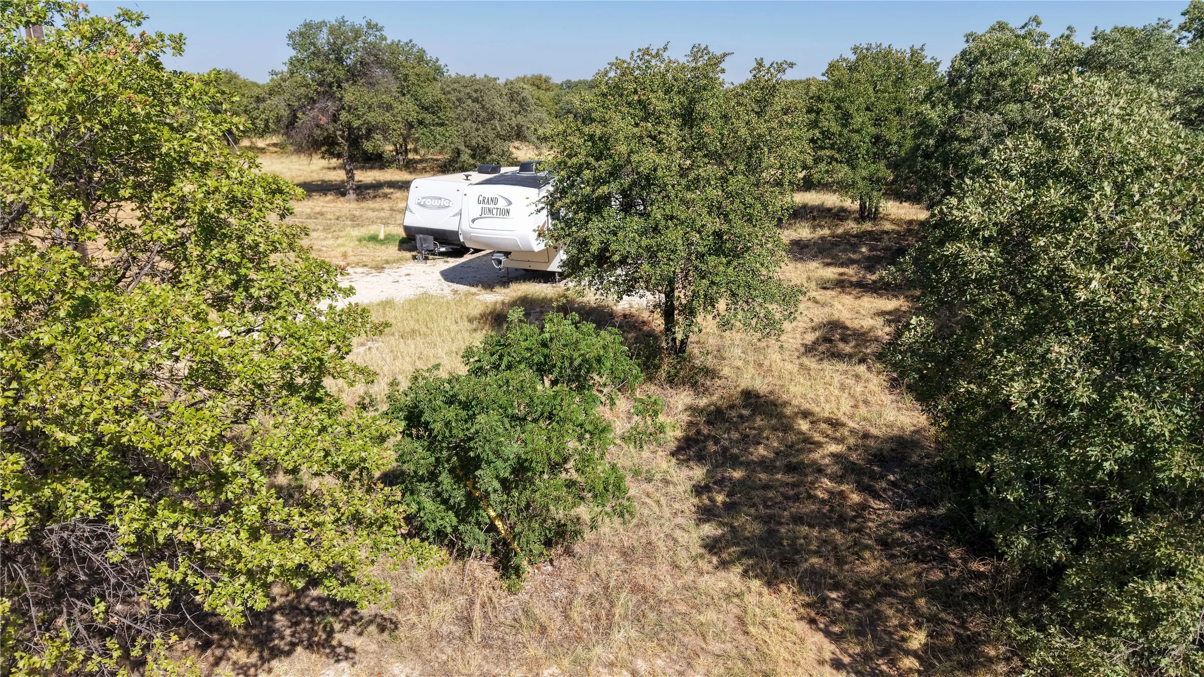 Wooded acreage with mature trees and a gravel pad