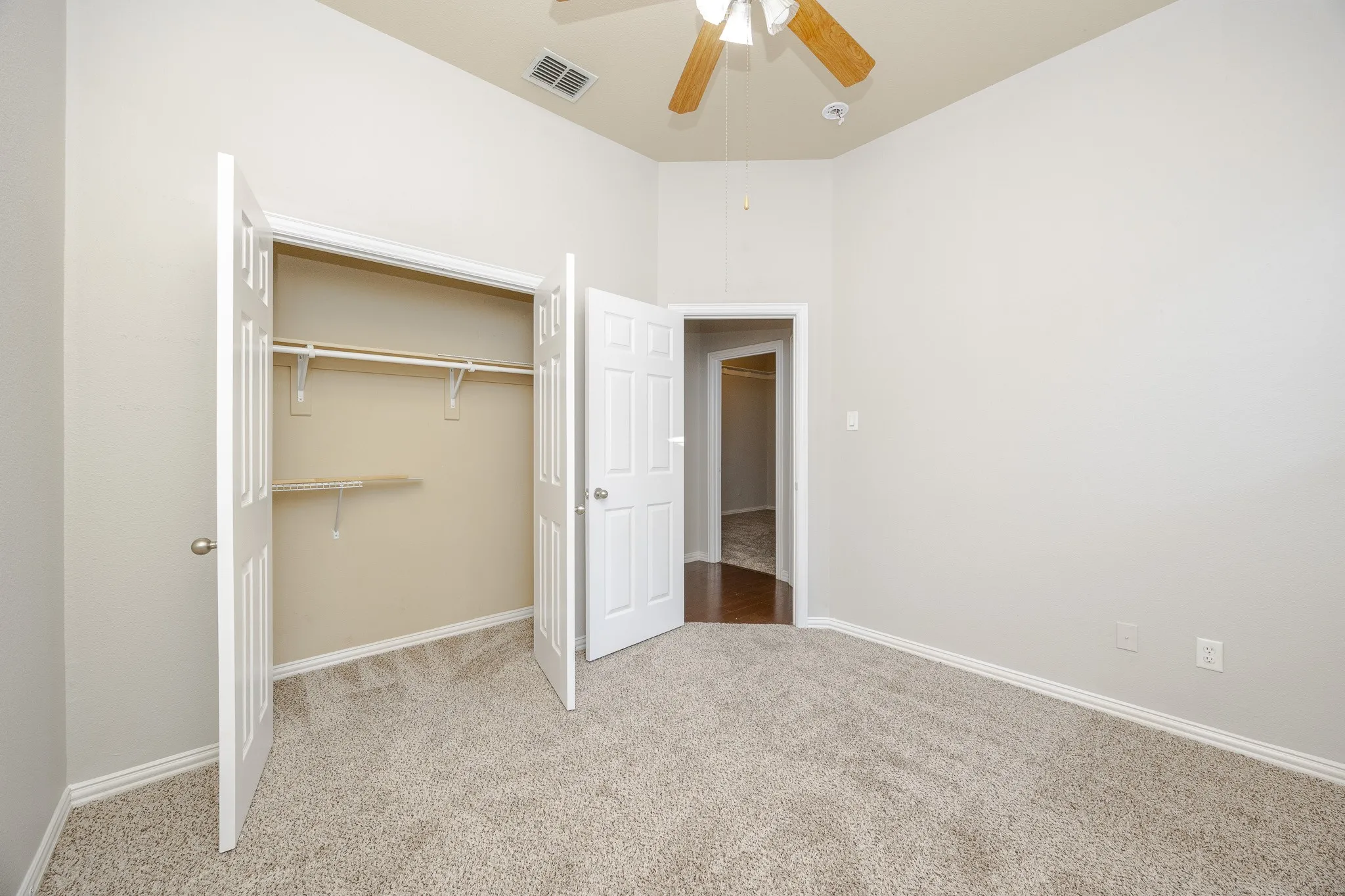 Vaulted ceiling, ceiling fan, carpet flooring, bi-fold closet doors, and interior closet shelving