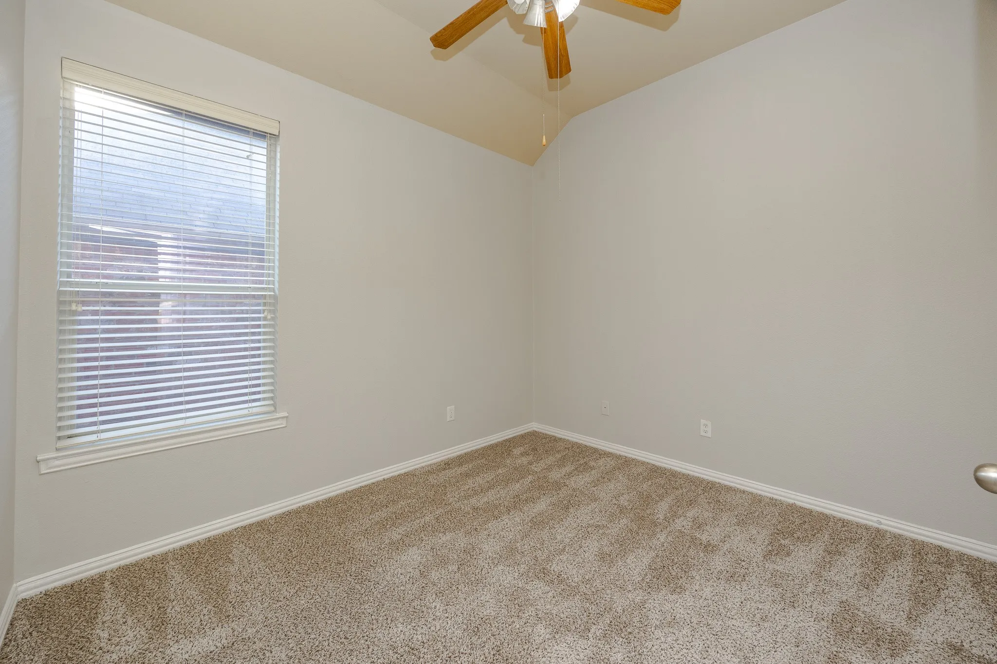 Neutral tone wall paint, vaulted ceiling, and ceiling fan with light fixture