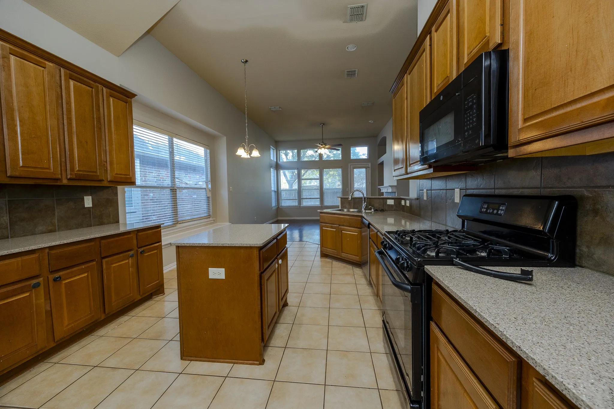 Kitchen featuring wood cabinetry, stone countertops, a tile backsplash, and a central island