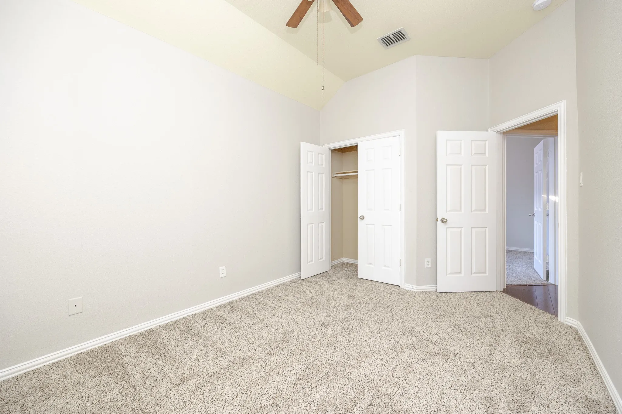 Vaulted ceiling with a ceiling fan, plush carpet flooring, and a double-door closet