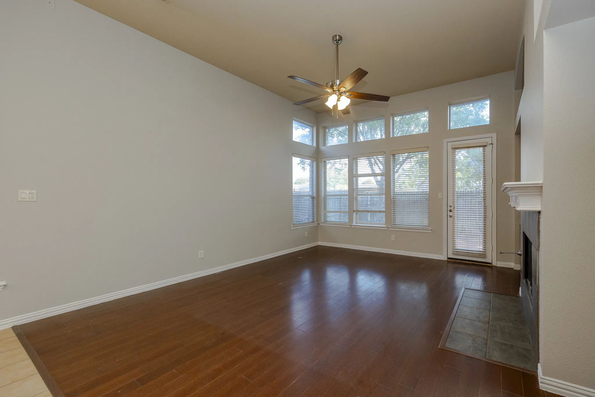Vaulted ceiling, hard-surface flooring, multiple windows, built-in fireplace, and a ceiling fan