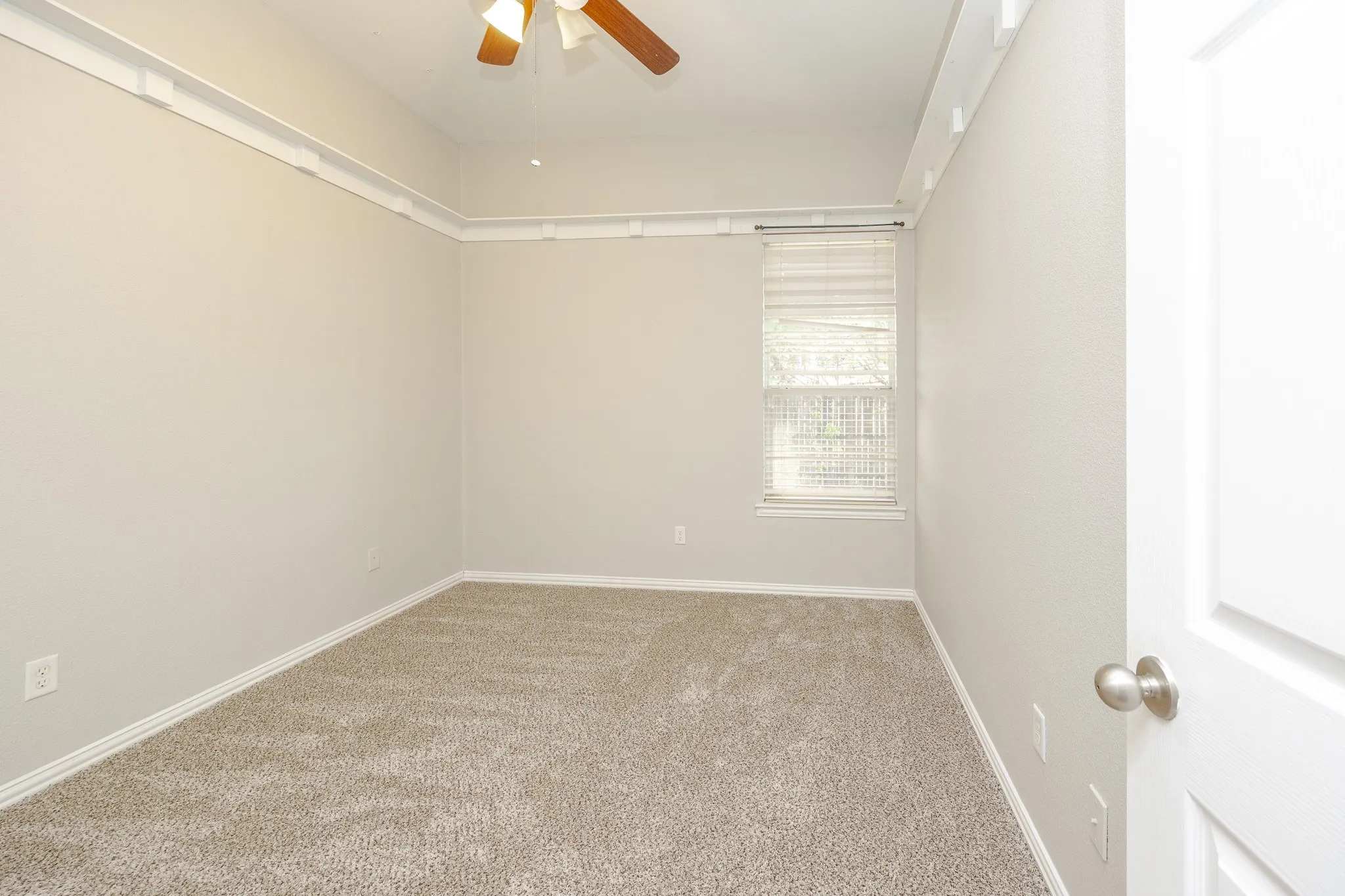 Recessed ceiling with white crown molding, light neutral paint, carpeted flooring, and a window with blinds