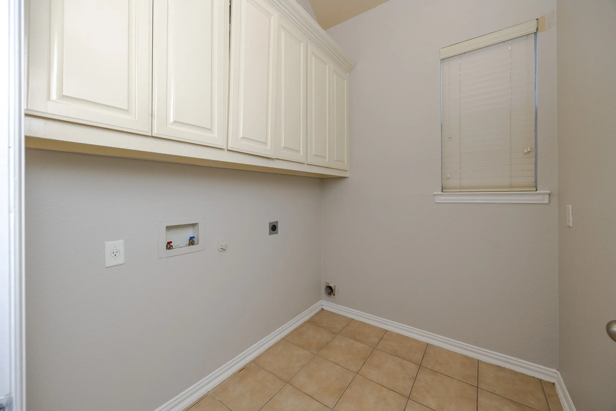 Tile flooring, built-in cabinetry, neutral wall color, and a window with blinds
