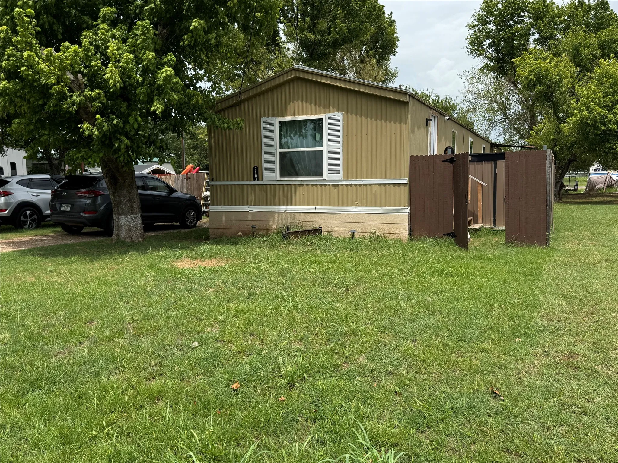 Single-story manufactured home featuring a corrugated metal exterior, light-colored window shutters, and a covered entry area