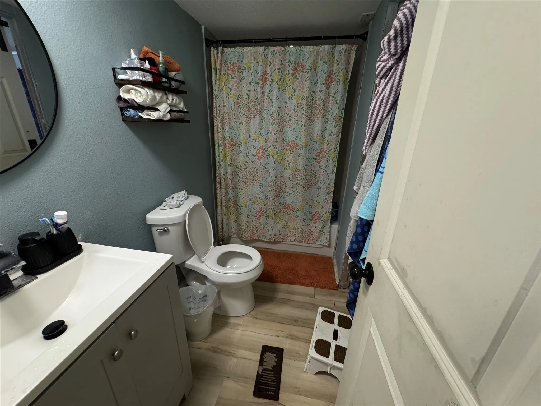 Bathroom featuring a single vanity with a rectangular basin, light wood-finish flooring, and a tub with shower