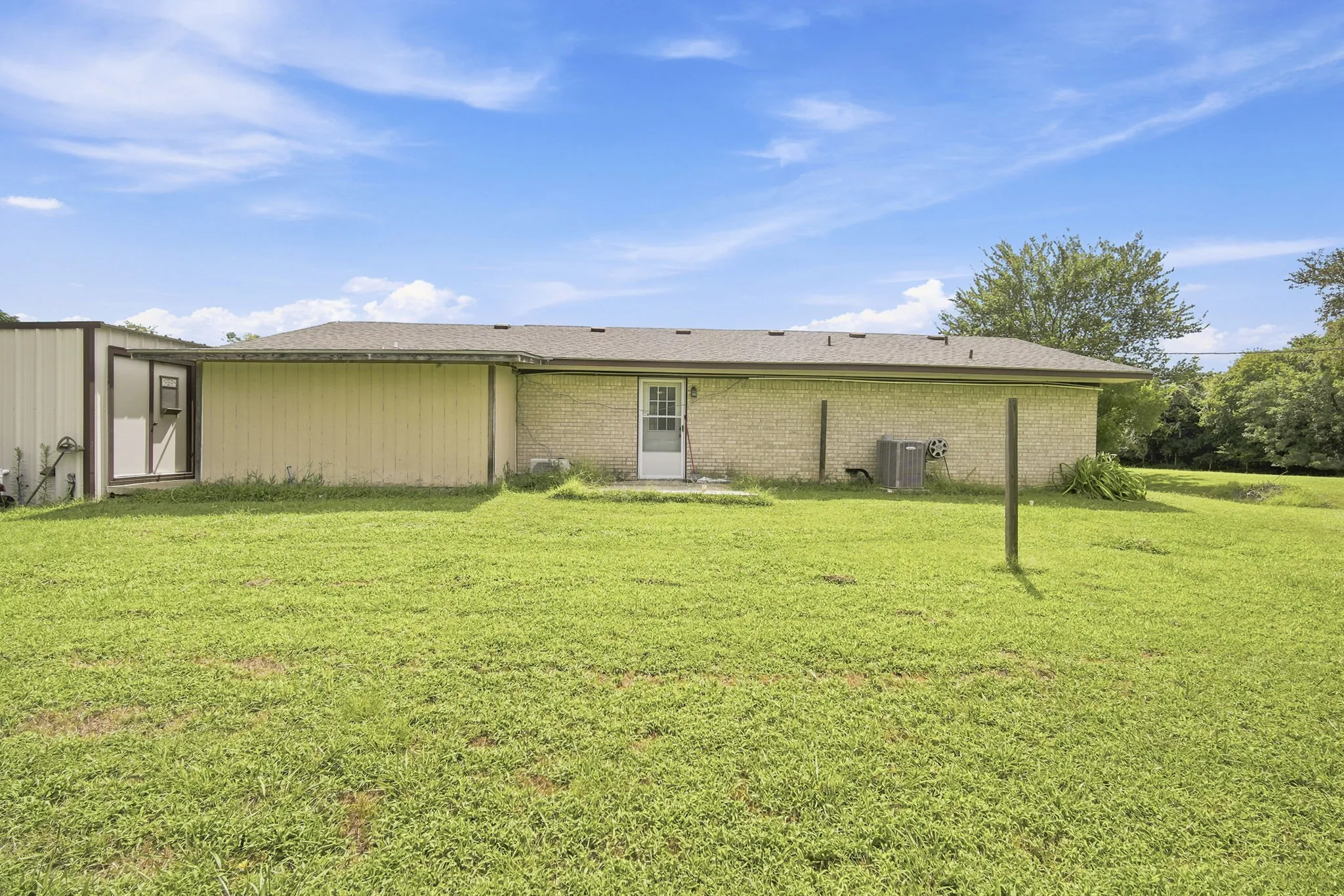 Spacious rear yard with a detached metal outbuilding and a brick-sided structure