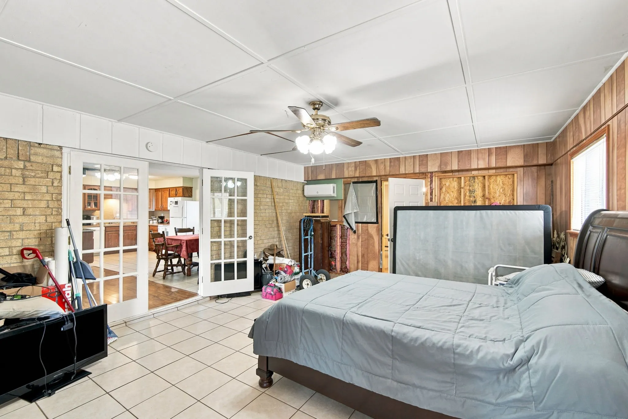 Spacious room featuring tile flooring, exposed brick wall, and wood paneling
