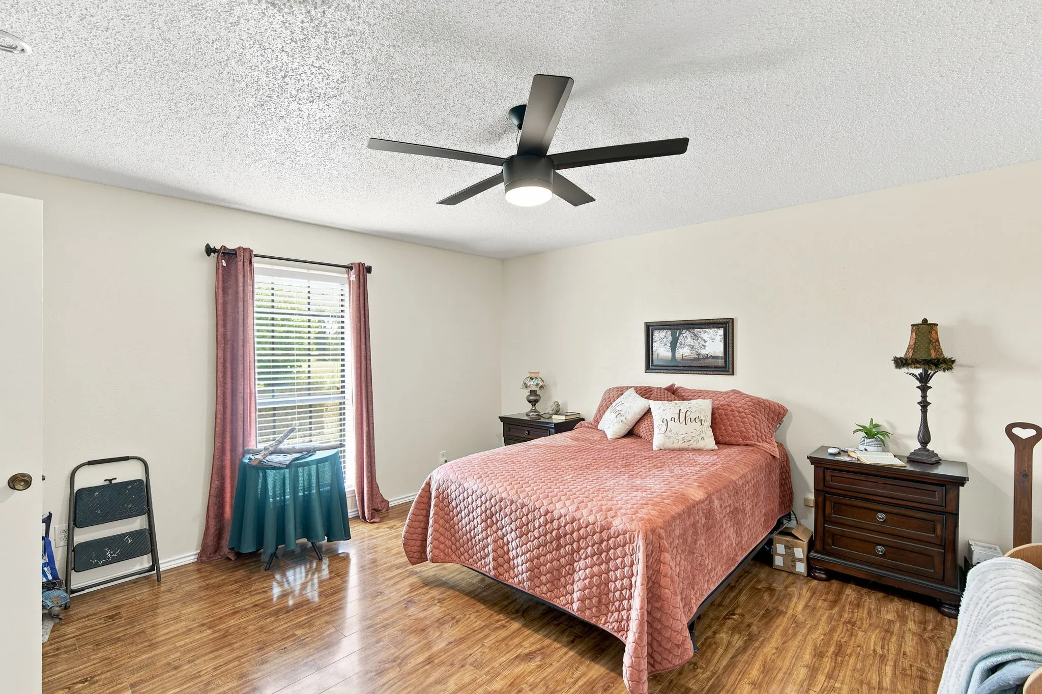 Bedroom featuring wood-finish flooring, a window with blinds, a ceiling fan with integrated lighting, and neutral wall tones