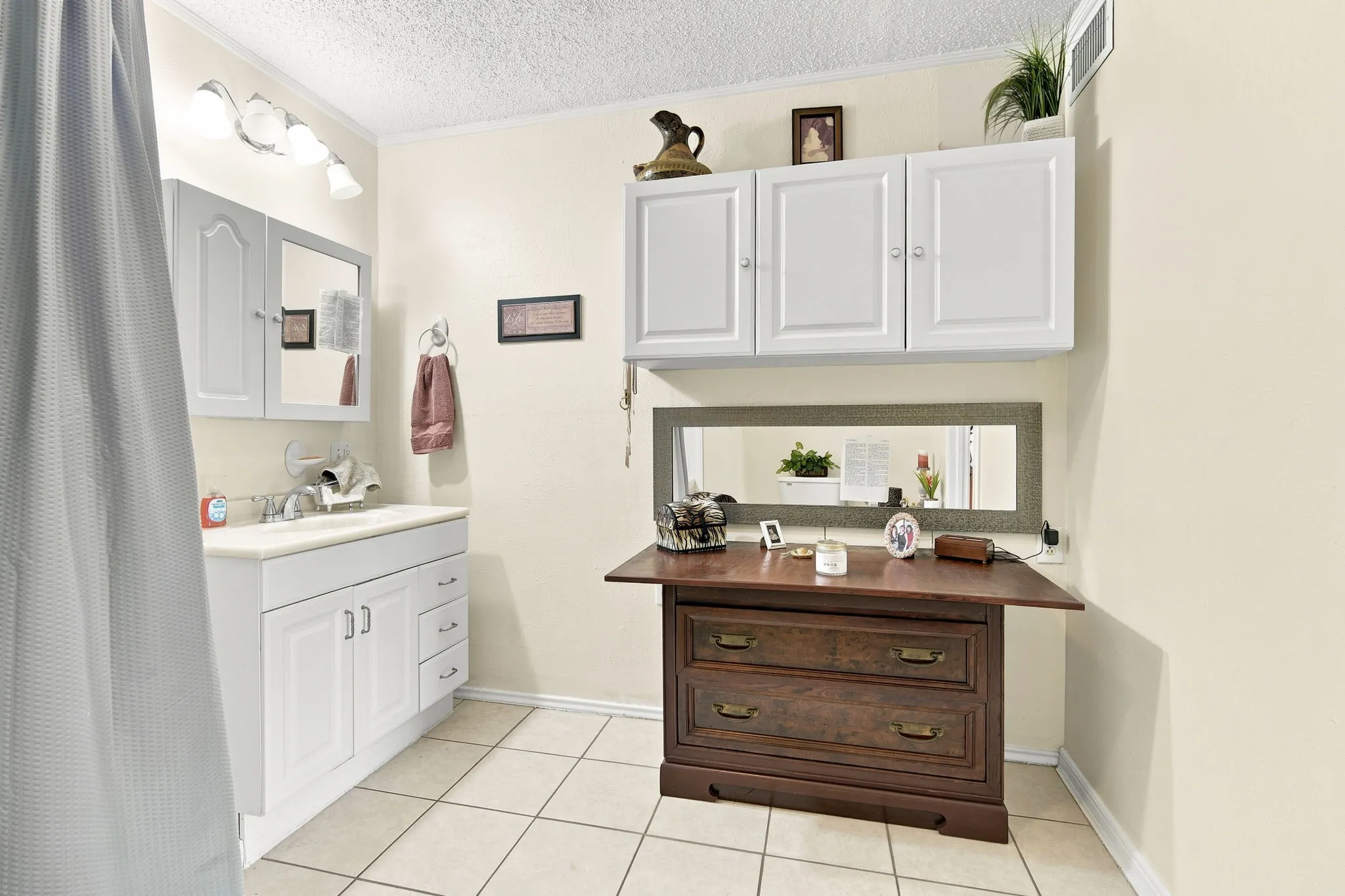 Bathroom featuring a single vanity with storage, medicine cabinet, overhead lighting, and tiled flooring