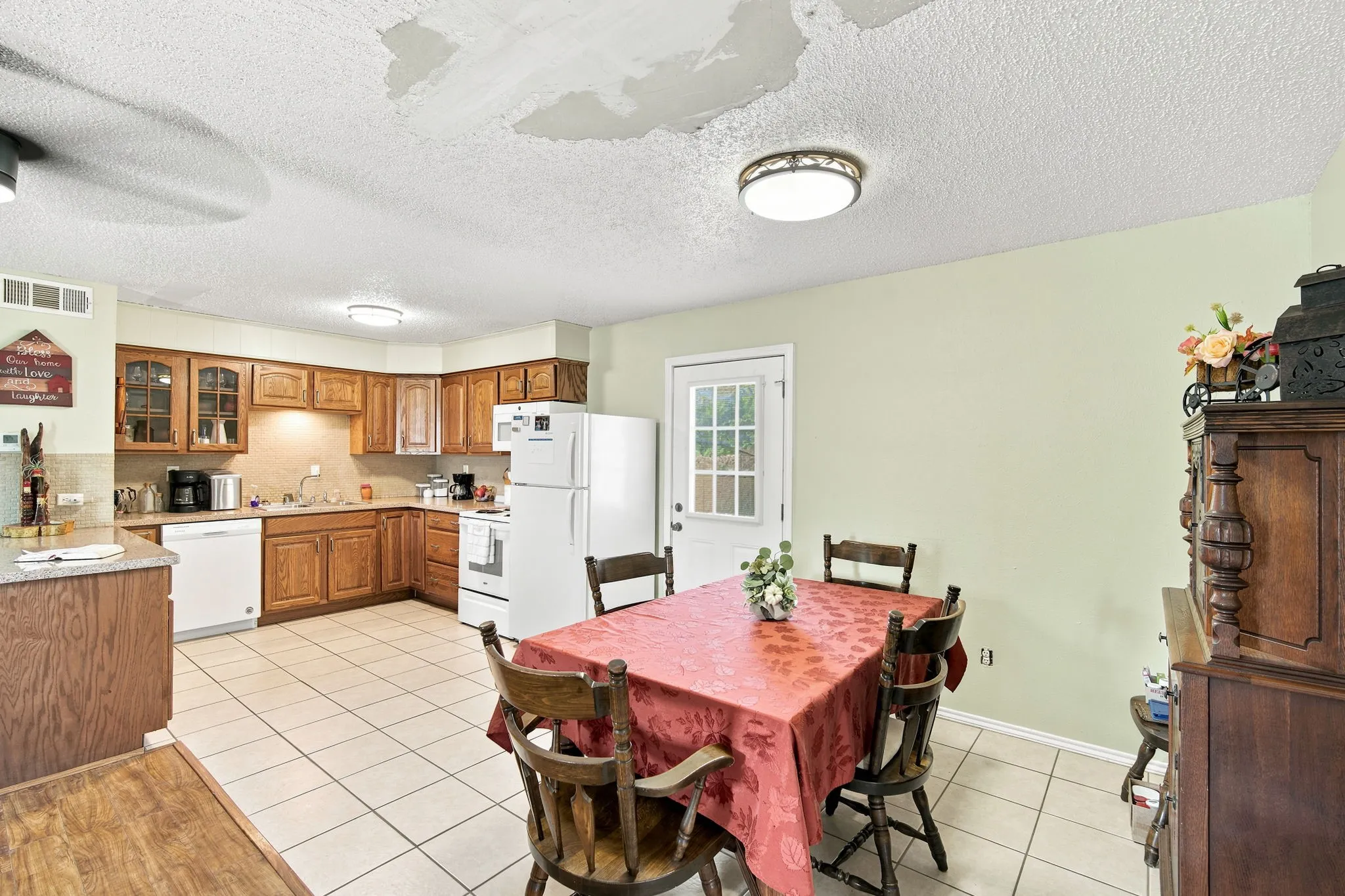Kitchen area featuring tile flooring, wood-finish cabinetry, white appliances, and a light green wall color