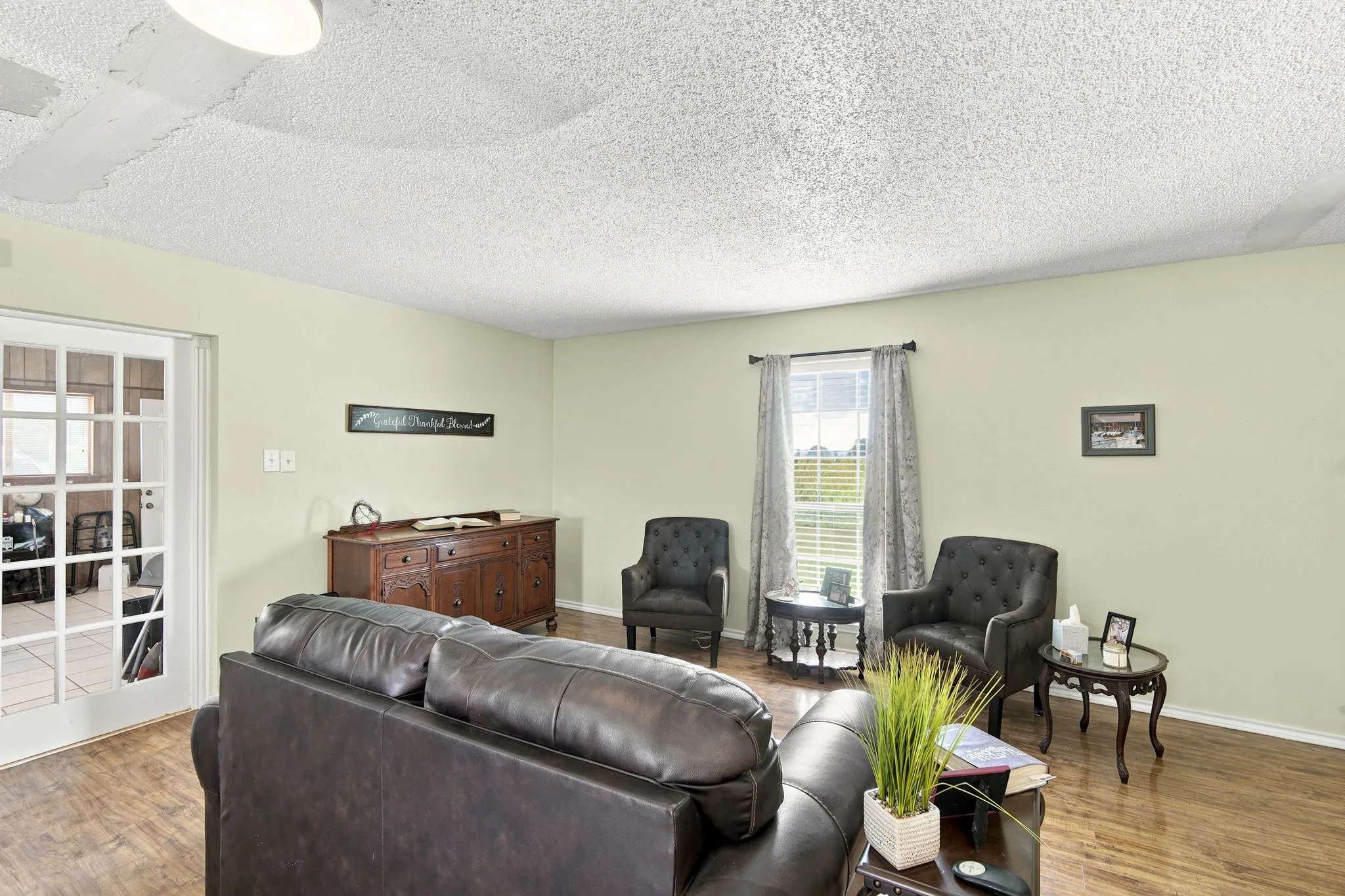Living area featuring wood-finish flooring, light-toned wall paint, and a textured ceiling