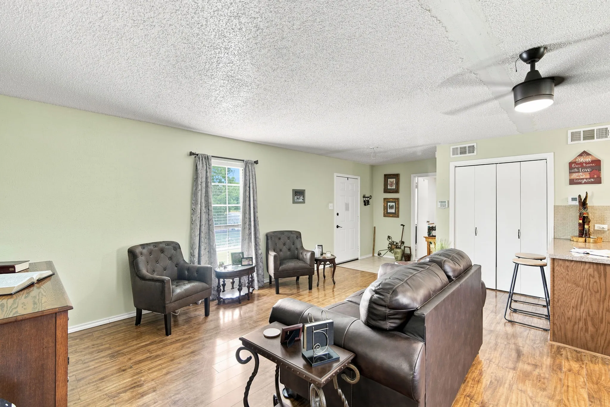 Living area featuring wood-finish flooring, light green wall paint, and a ceiling fan with integrated lighting
