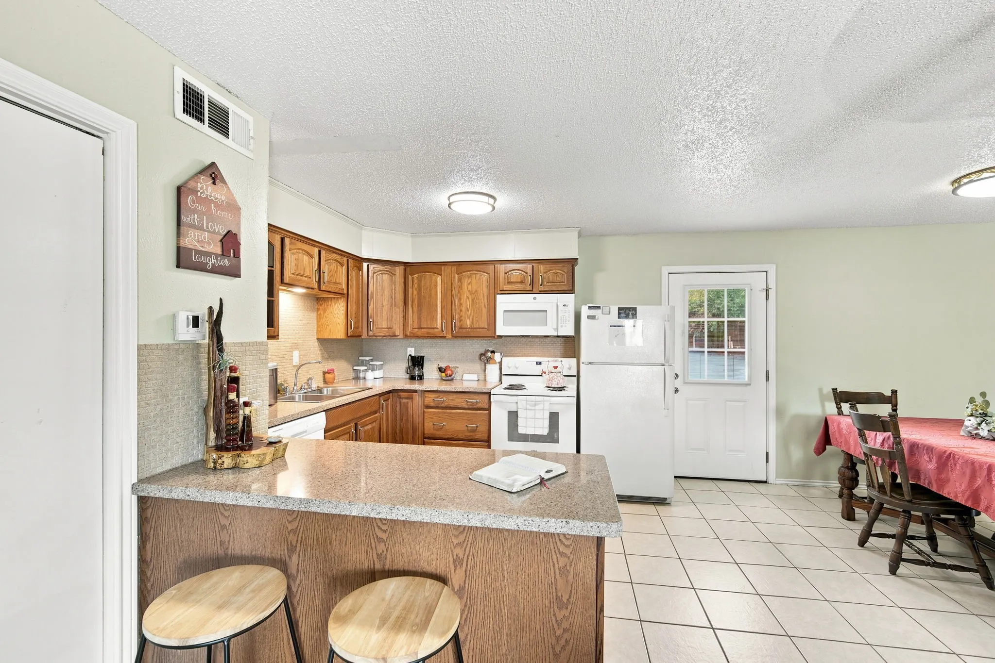 Kitchen with wood-finish cabinetry, light-toned countertops, and tile flooring