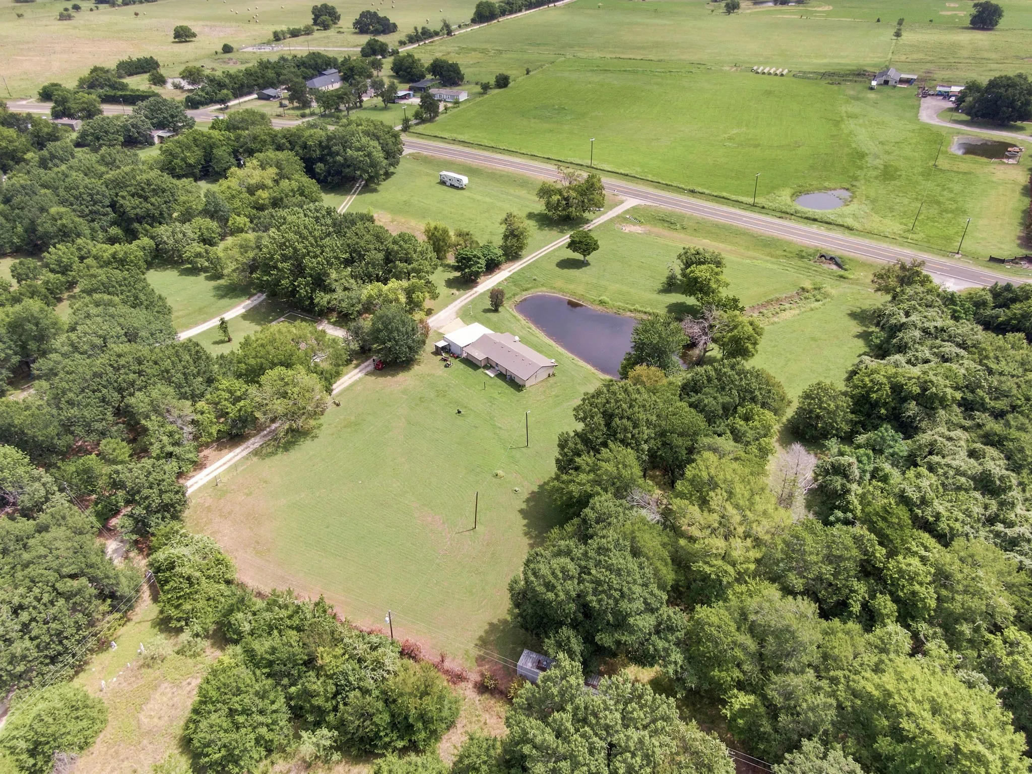 Expansive rural property featuring a main residence, a private pond, and abundant mature trees