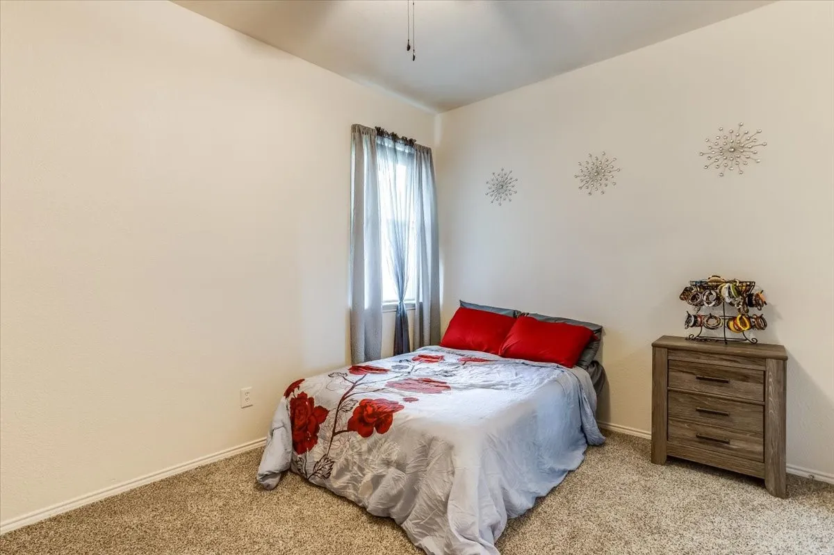 Carpeted room with a ceiling fan and window