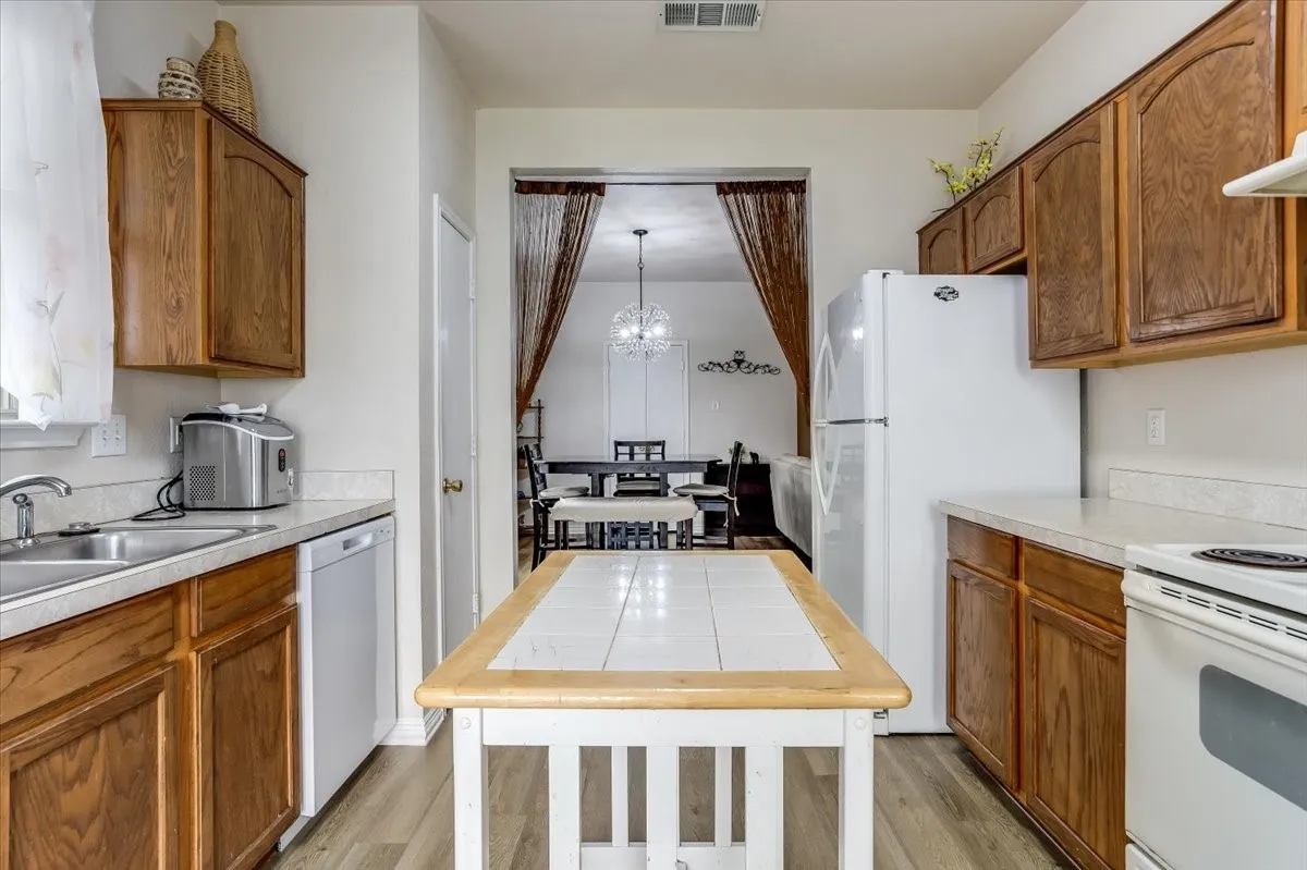 Kitchen featuring wood-finish cabinetry, countertops, a stainless steel sink, and luxury vinyl plank flooring